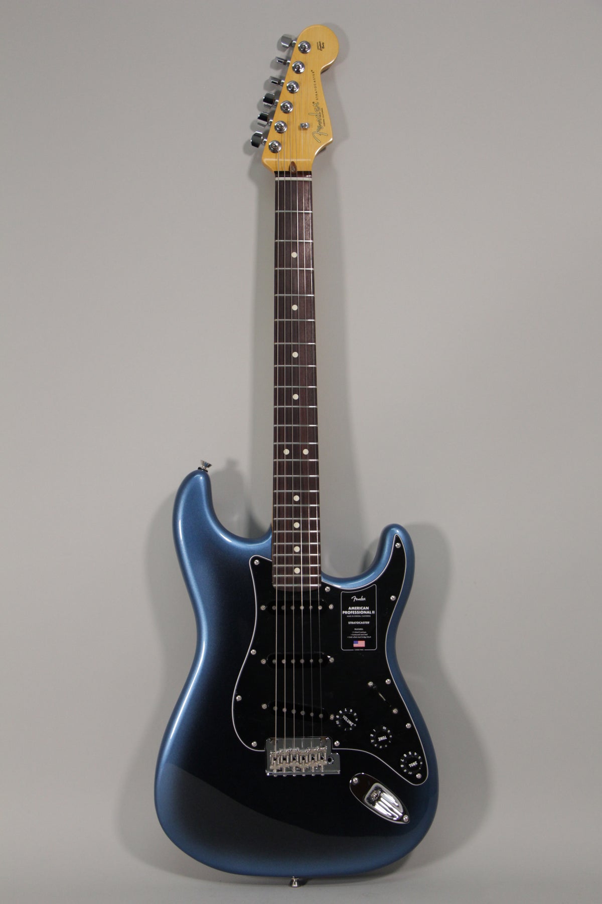 Full-length view of a metallic dark blue Stratocaster with a black pickguard, three single-coil pickups, and a maple neck.