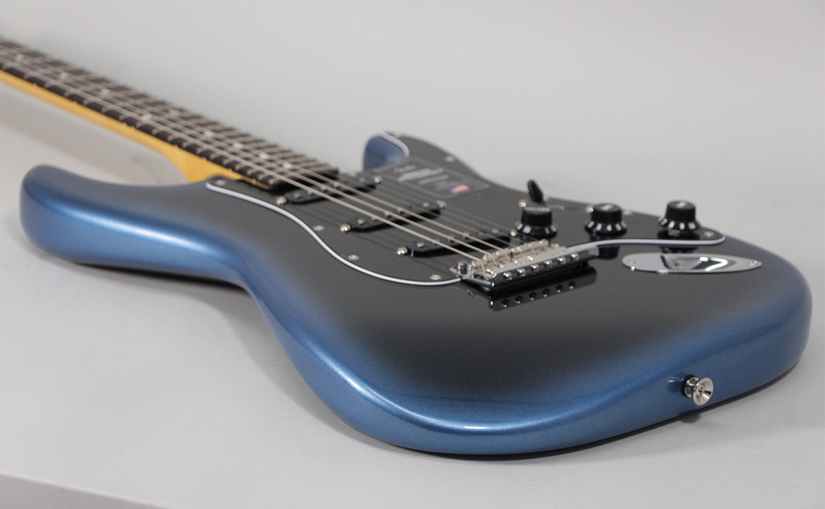 The electric guitar's dark blue metallic body and black pickguard are angled from the lower right, with the neck extending left.