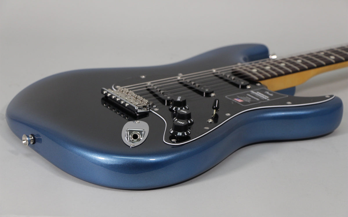 The metallic dark blue Stratocaster body is angled from the lower bout, showing the black pickguard, controls, and chrome bridge.