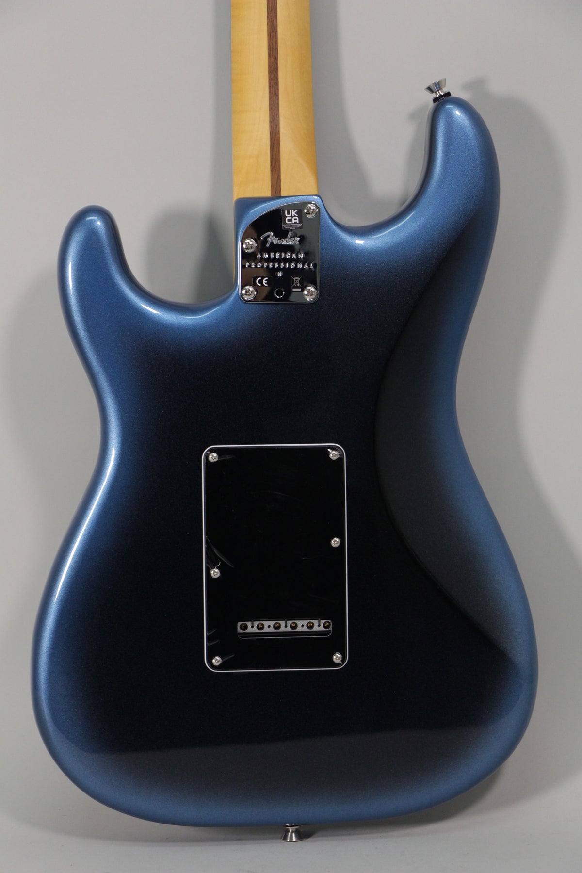 The back of a dark blue metallic Stratocaster body, with a maple neck, chrome neck plate, and black tremolo cover.