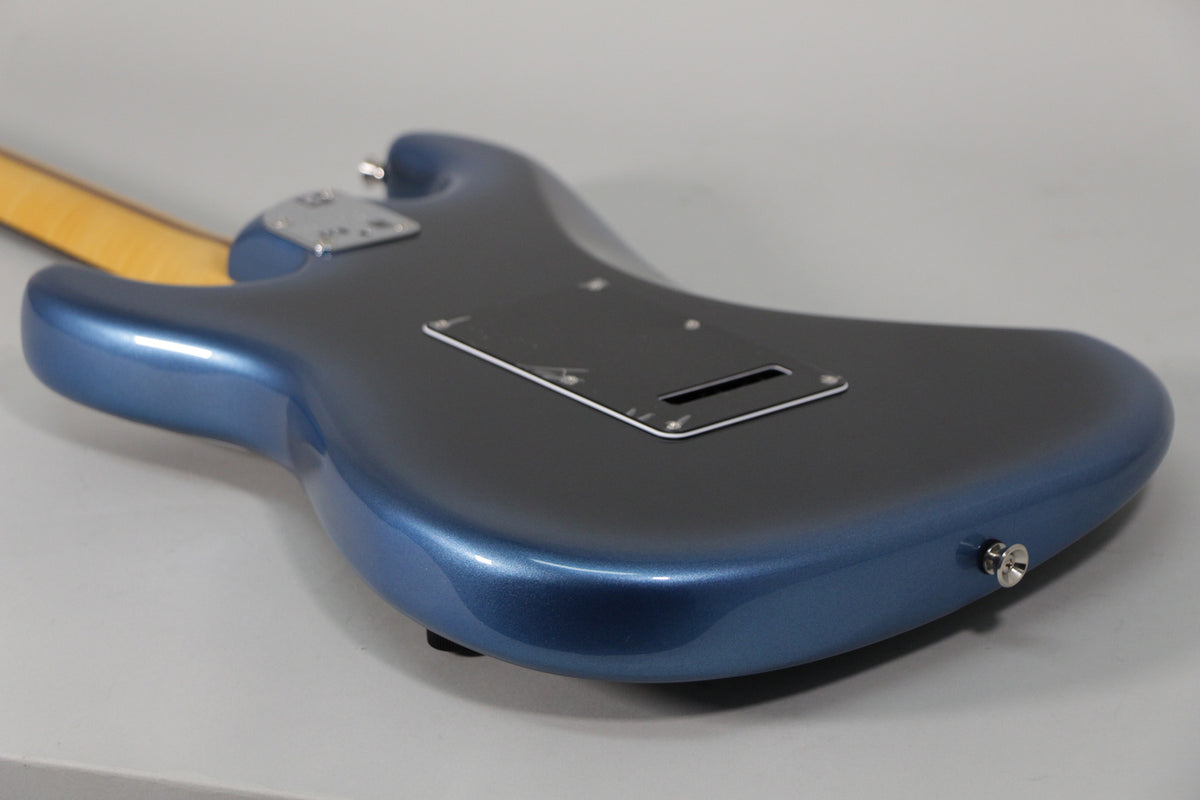 The back of a metallic dark blue Stratocaster body, showing the tremolo cavity cover and a chrome strap button.