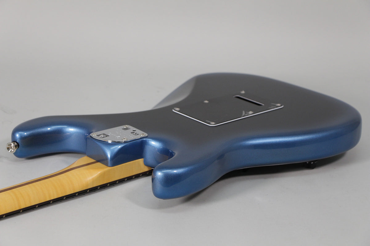 The back of the metallic dark blue guitar body is angled, showing the neck plate, output jack, and black tremolo cavity cover.