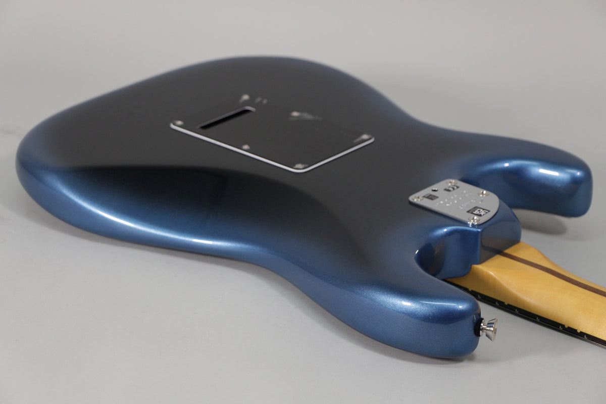 The back of a dark blue metallic Stratocaster body, angled from the lower bout, showing the tremolo cavity cover and neck plate.