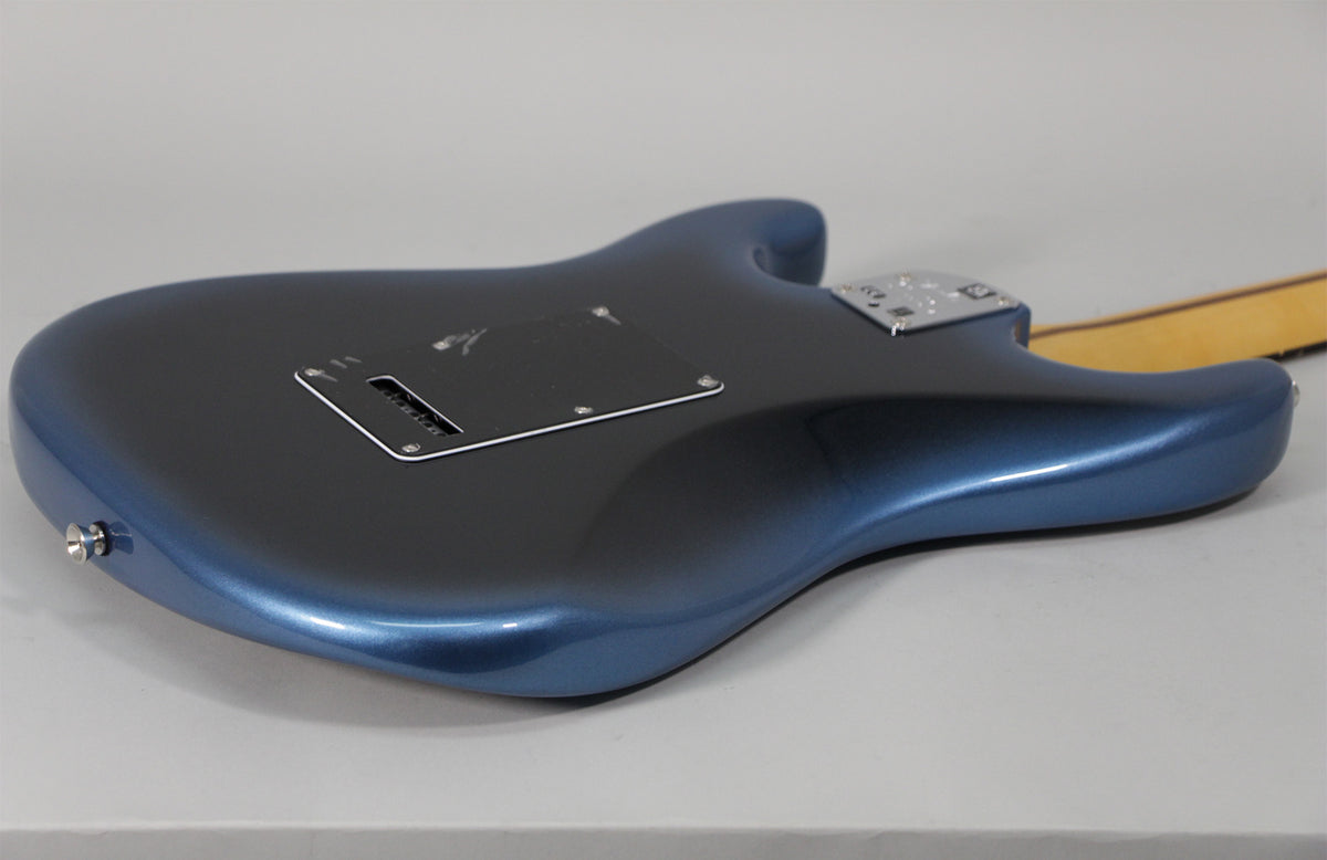The guitar's dark blue metallic body is shown from the back, angled right, revealing the tremolo cavity cover and neck plate.