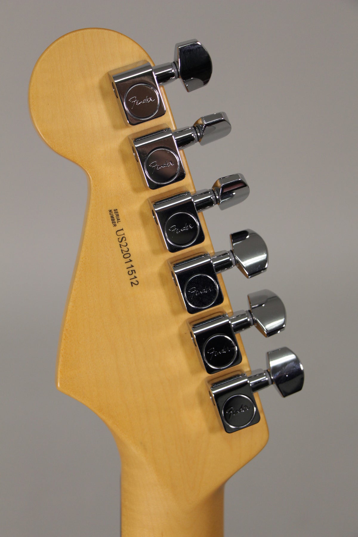 The back of a light-colored maple headstock and neck, with six chrome tuning machines visible.
