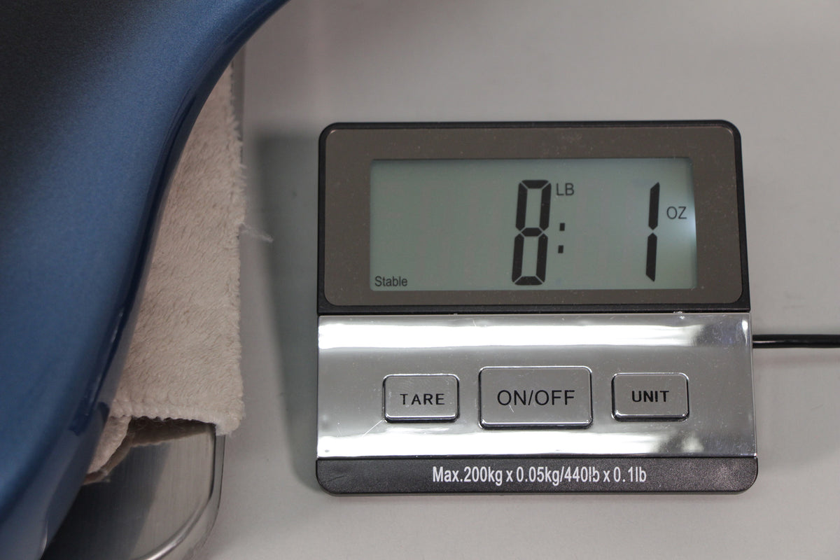 A close-up of the guitar's dark blue body resting on a scale, displaying a weight of 8 pounds, 1 ounce.