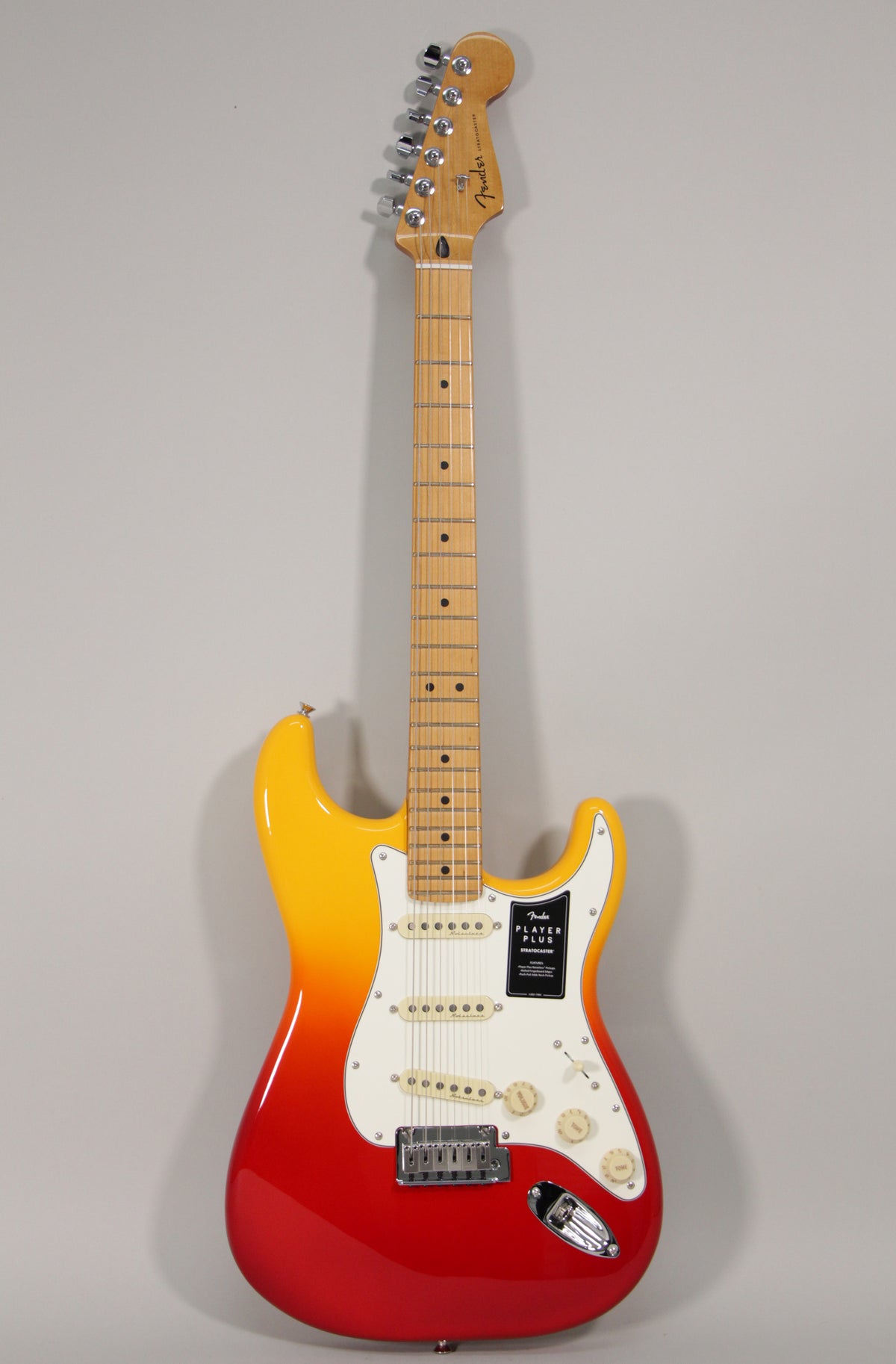 Full-length view of a Stratocaster with a red-to-yellow sunburst finish, white pickguard, three single-coil pickups, and a maple neck.