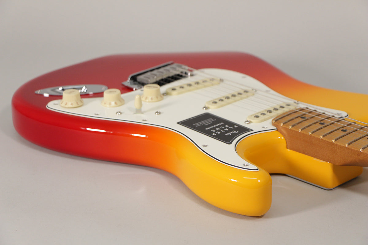 The Stratocaster's glossy red-to-yellow burst finish is visible from the lower bout, with a white pickguard and cream controls.