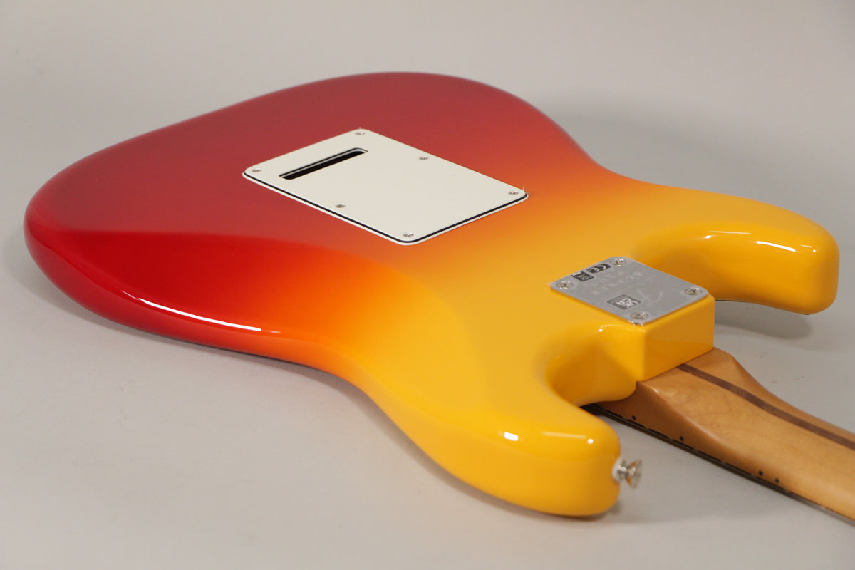 The guitar's glossy back, in a red-to-yellow burst, shows a white tremolo cover and a chrome neck plate, with no visible wear.
