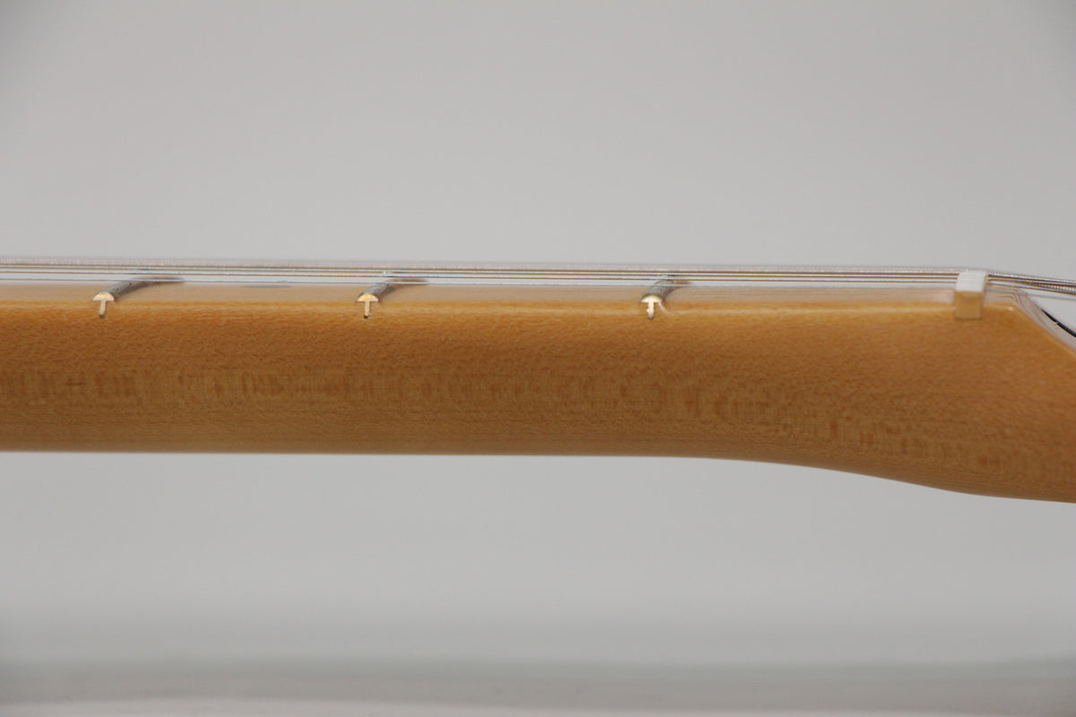 Close-up of a guitar neck with a light brown finish, showing three frets and strings, against a plain white background.