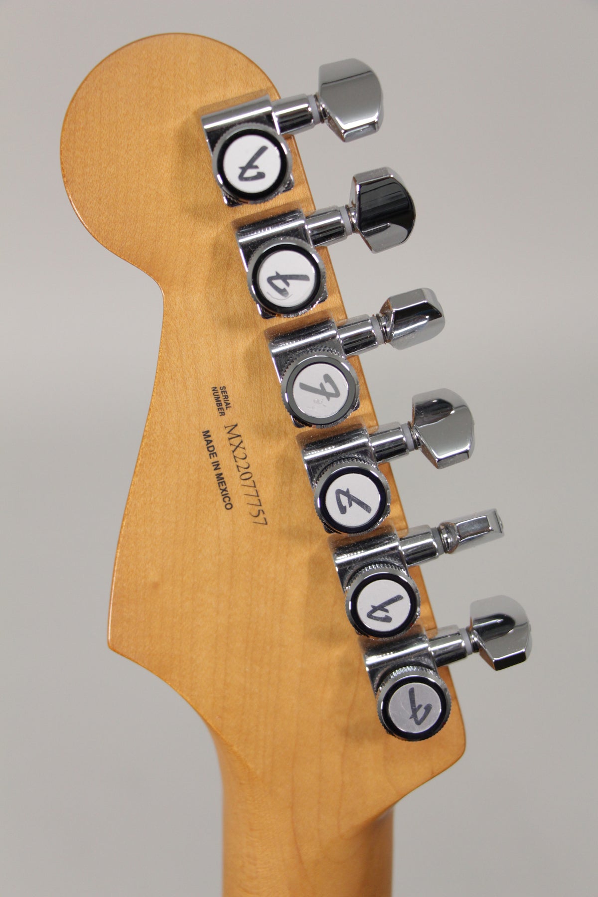 The back of the guitar's headstock, light wood with a satin finish, showing six chrome tuners with white-ringed buttons.