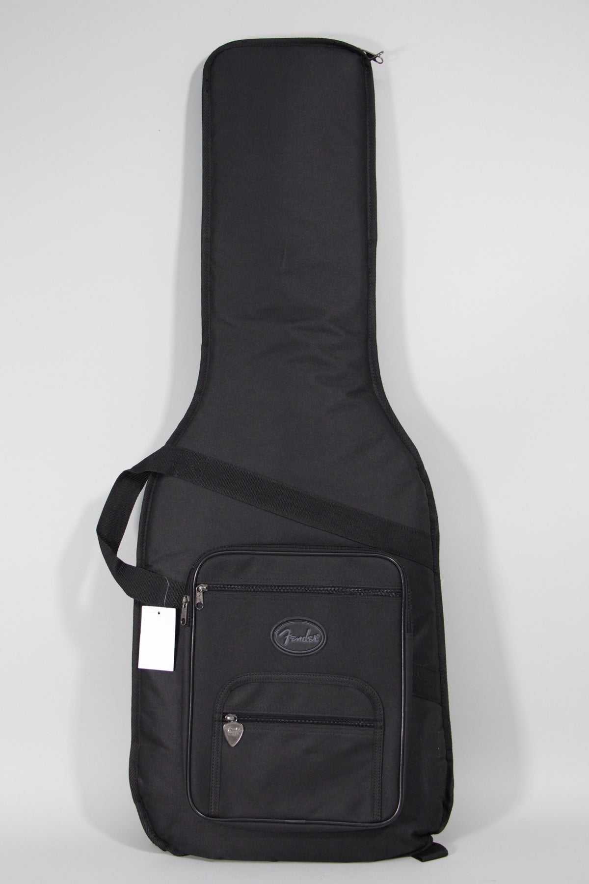 Full-length view of a black soft guitar bag with a shoulder strap, two zippered pockets, and a blank white tag hanging from a zipper.