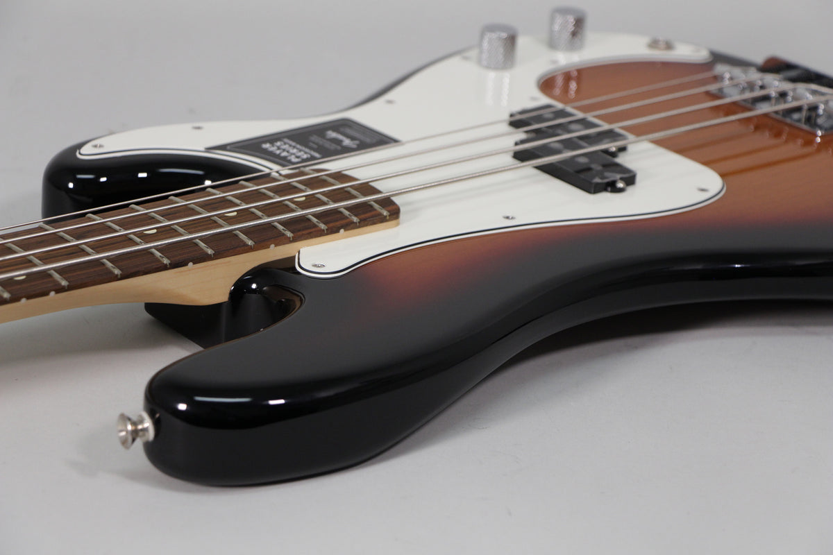 The sunburst Precision Bass body, with a white pickguard and split pickup, is angled from the lower bout towards the neck.