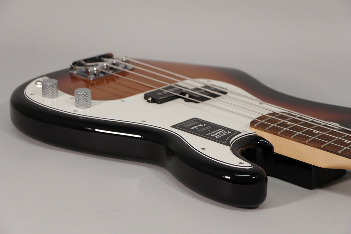 Close-up of a sunburst Precision Bass, showing the lower body, white pickguard, chrome knobs, and split pickup from above.