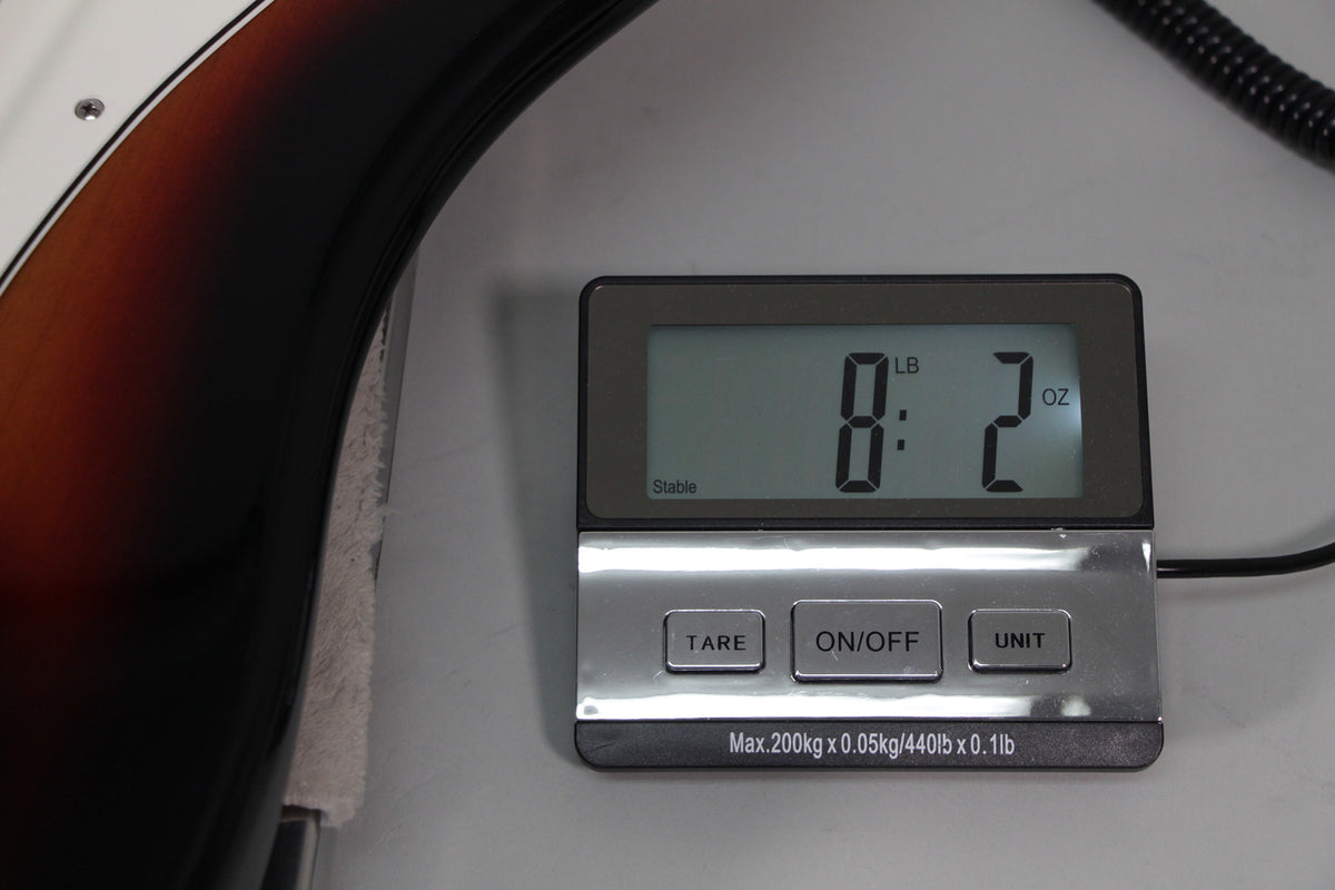 The bass body's sunburst finish is visible on the left, next to a digital scale displaying "8 LB : 2 OZ".