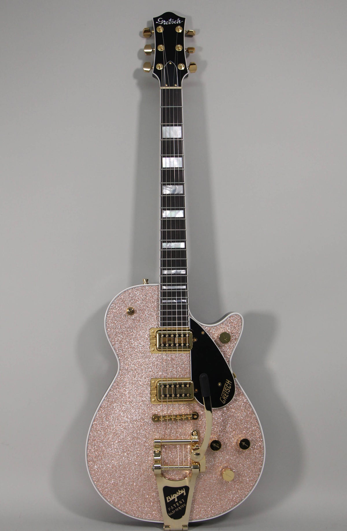 Full-length view of a rose gold sparkle guitar with gold hardware, black pickguard, Bigsby tremolo, and block inlays.