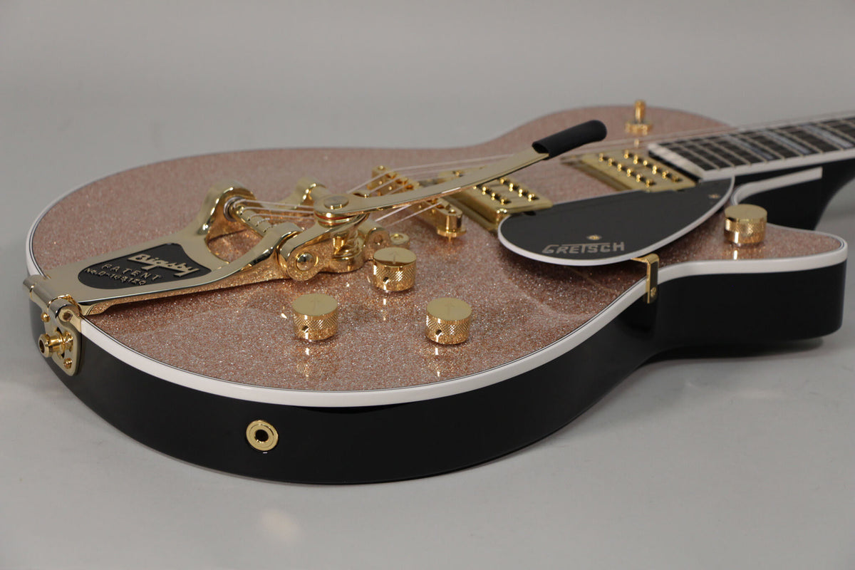Close-up of the rose gold sparkle top and black sides, showing the gold Bigsby vibrato, pickguard, and control knobs.