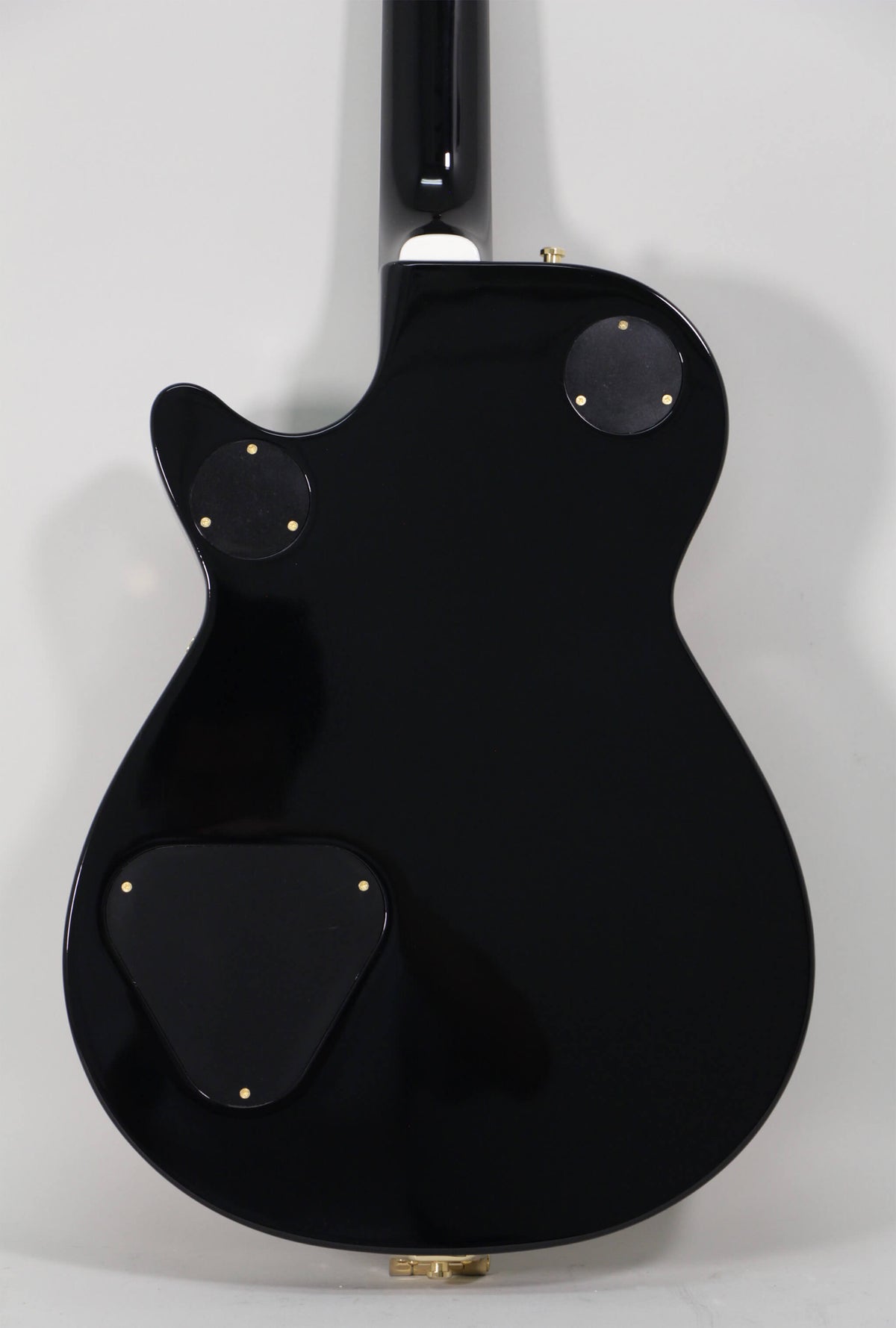 The guitar's glossy black back is shown, featuring three black control cavity covers with gold screws and a gold strap button.