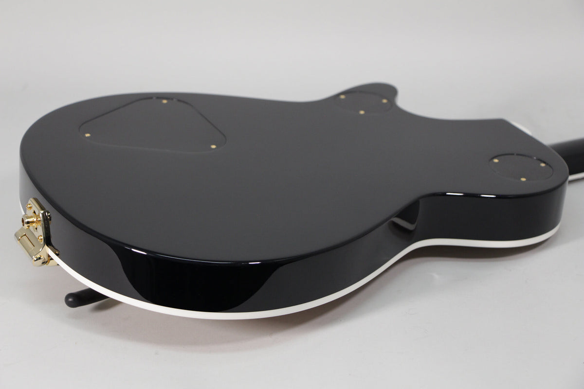 The guitar's glossy black back and sides are visible, with white binding and gold hardware, including a jack plate.
