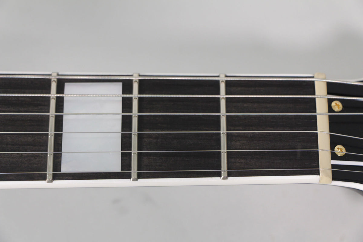 Close-up of the dark fretboard with rectangular pearloid inlays, silver frets, and a cream nut.