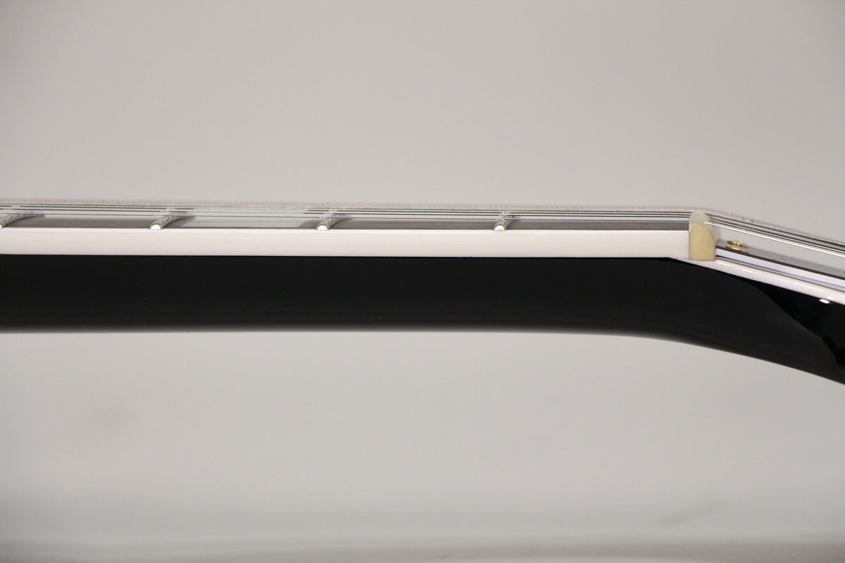 Close-up of the guitar's black neck and white binding, showing the nut and the first few frets from a side angle.