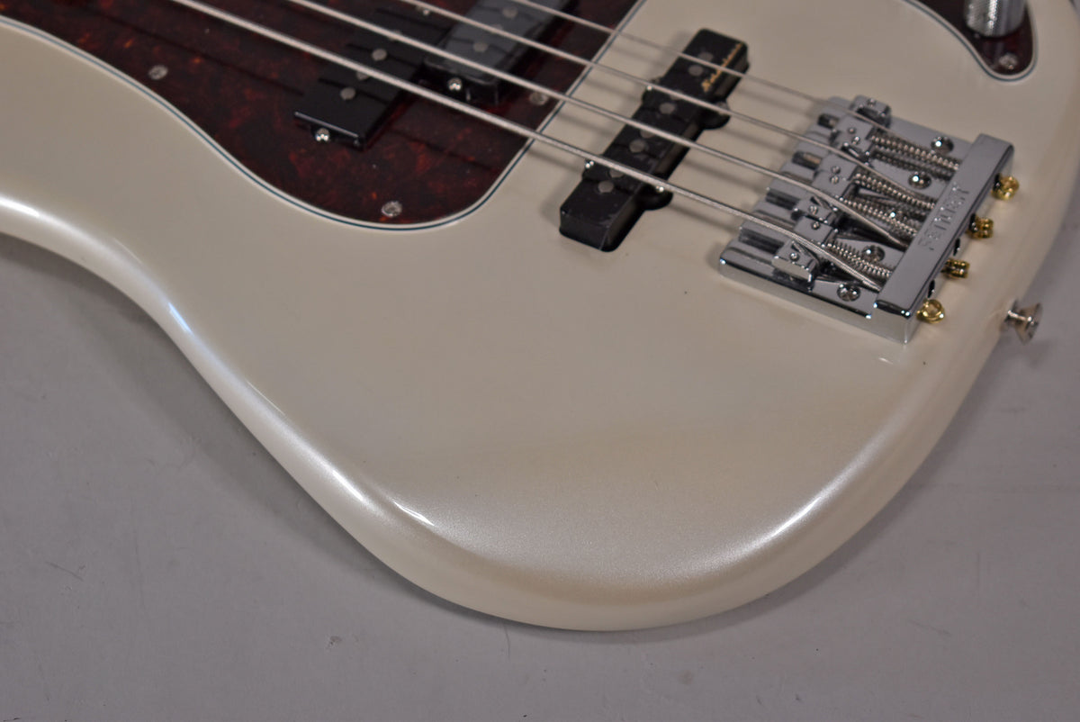 Close-up of the bass body's lower bout, showing the pearlescent white finish, chrome bridge, and dark tortoiseshell pickguard.