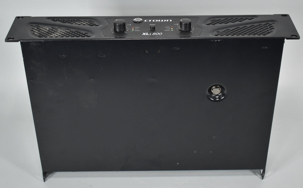 A black power amplifier, viewed from above and slightly to the front, showing two large control knobs and a row of small indicator lights.