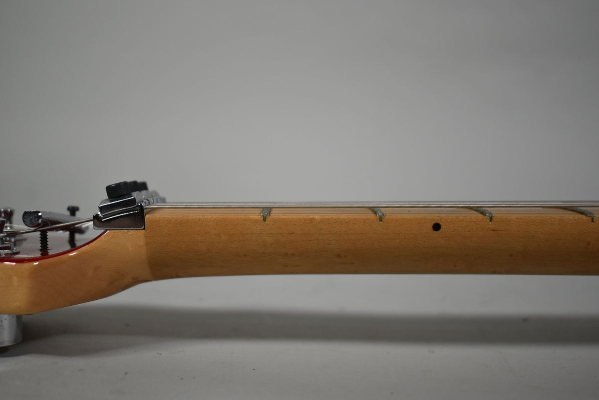 Side view of the guitar neck and headstock, showing a maple fretboard with dot inlays and a locking nut.