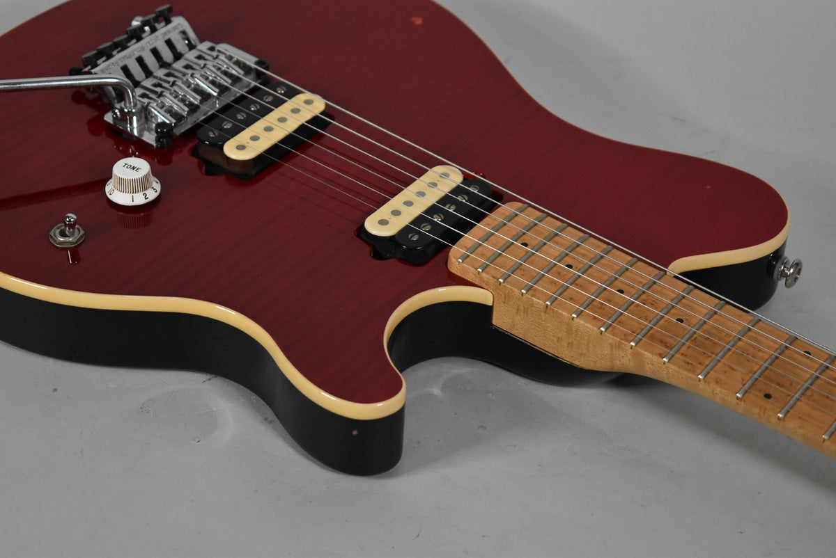 Upper body of a trans red flame top guitar with cream binding, two cream humbuckers, a tremolo, and a maple neck.