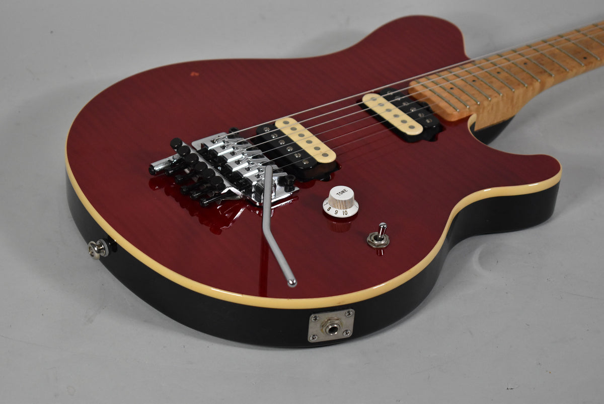 Close-up of the guitar's lower body, showing the red flame top, cream binding, Floyd Rose tremolo, and a single white tone knob.