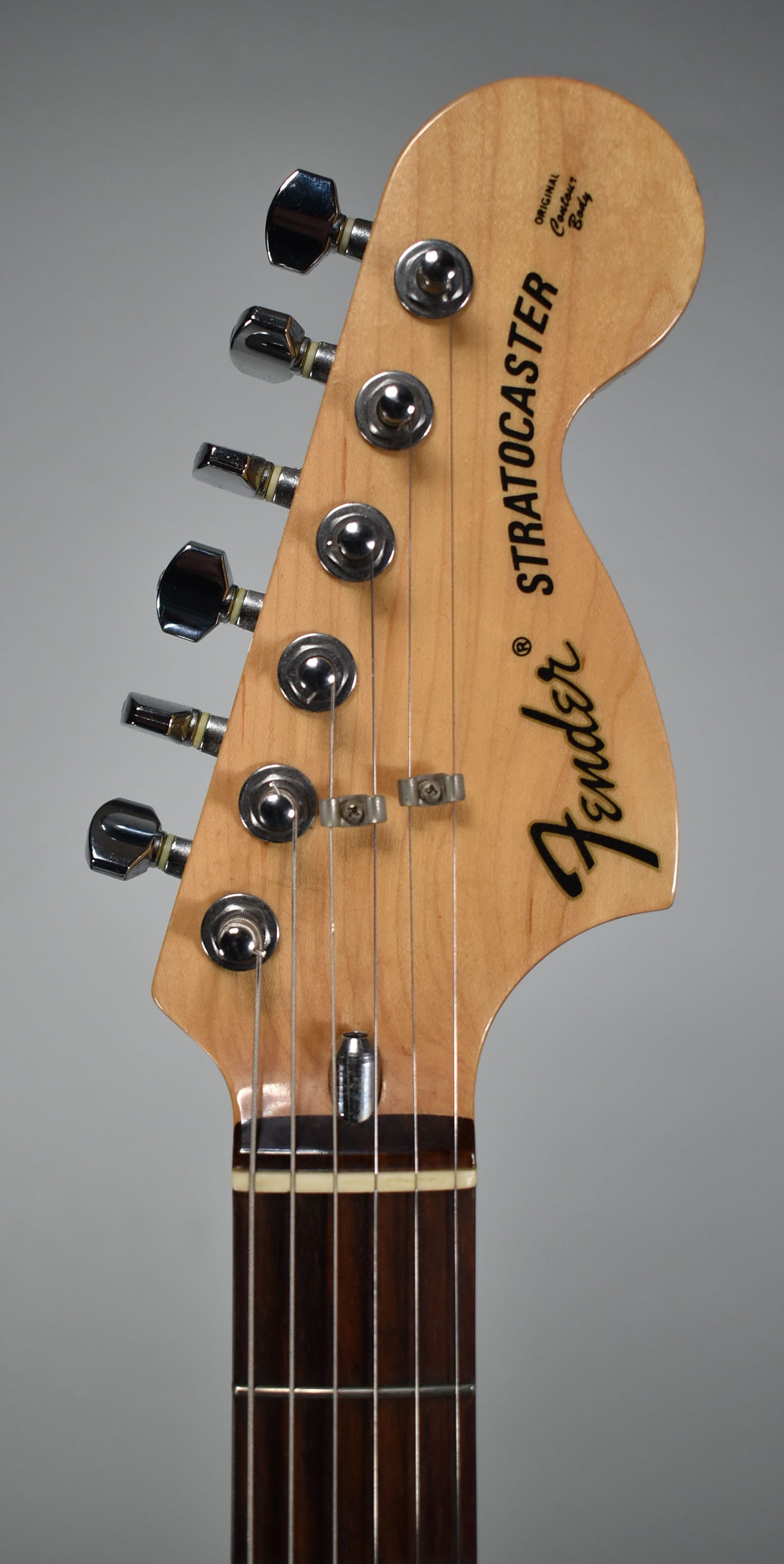 Close-up of the light maple headstock with six chrome tuners and two string trees, showing a dark rosewood fretboard.