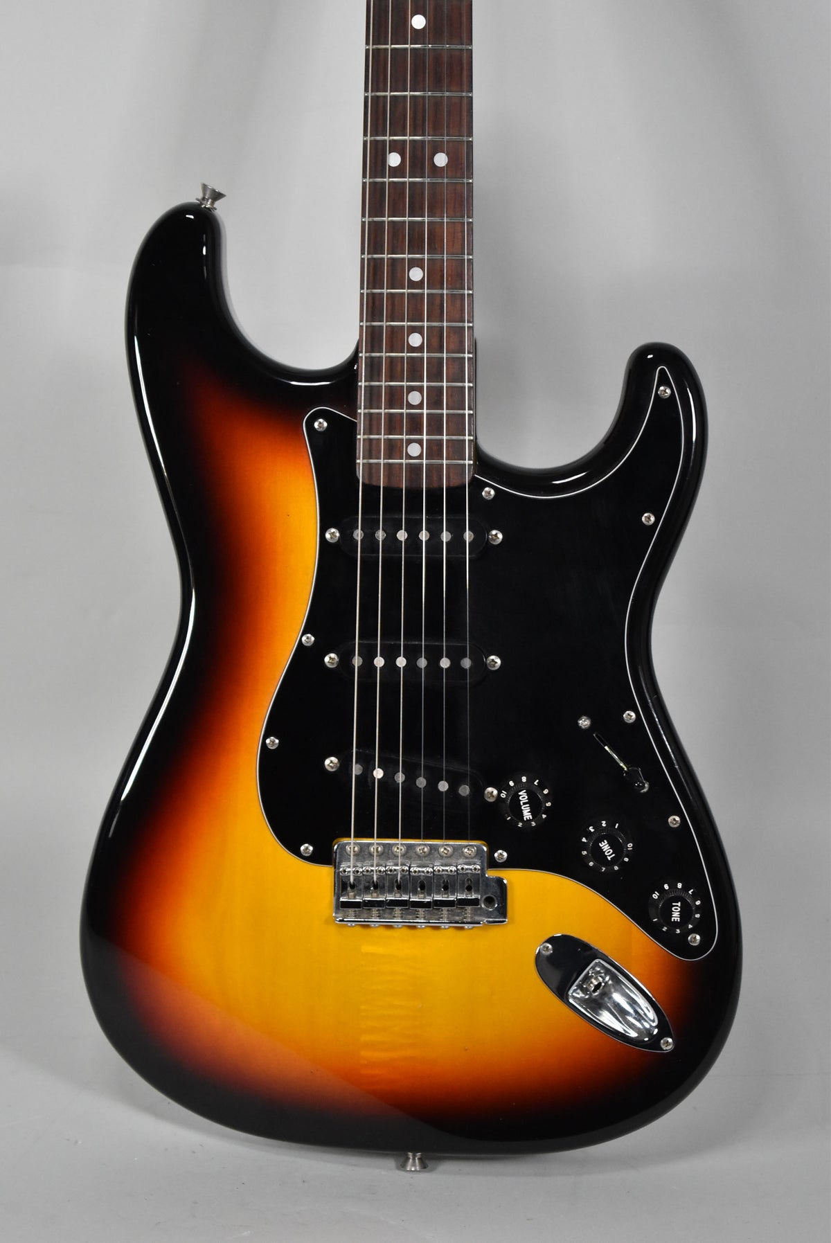 Full-frame view of a glossy three-tone sunburst Stratocaster with a black pickguard, three single-coil pickups, and chrome hardware.