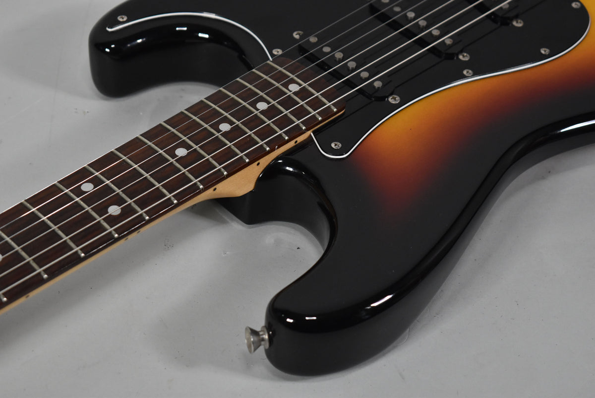 Close-up of the guitar body and lower neck, showing the glossy three-tone sunburst finish and black pickguard.