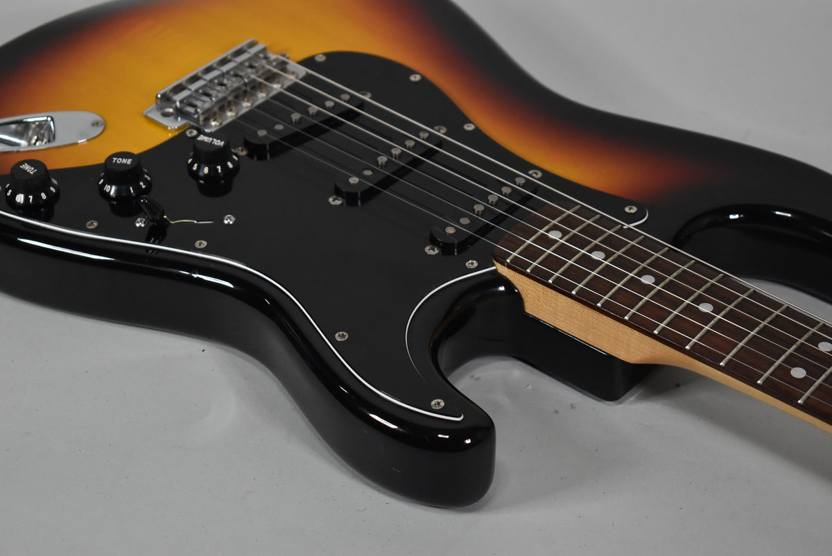 Close-up of the guitar's lower body, showing the three-tone sunburst finish, black pickguard, three single-coil pickups, and control knobs.