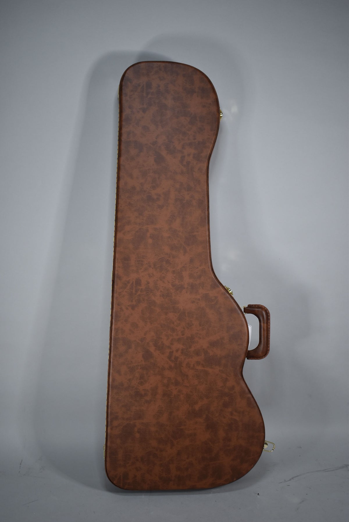 A brown, textured guitar case with gold-colored latches and a matching handle, viewed from the side.