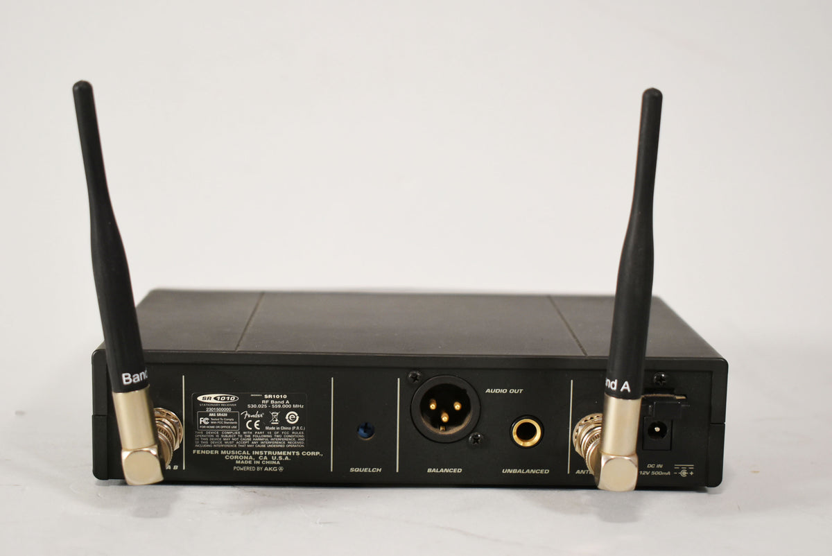 Rear view of a matte black wireless receiver with two upward-angled antennas, XLR and 1/4" audio outputs, and a squelch knob.
