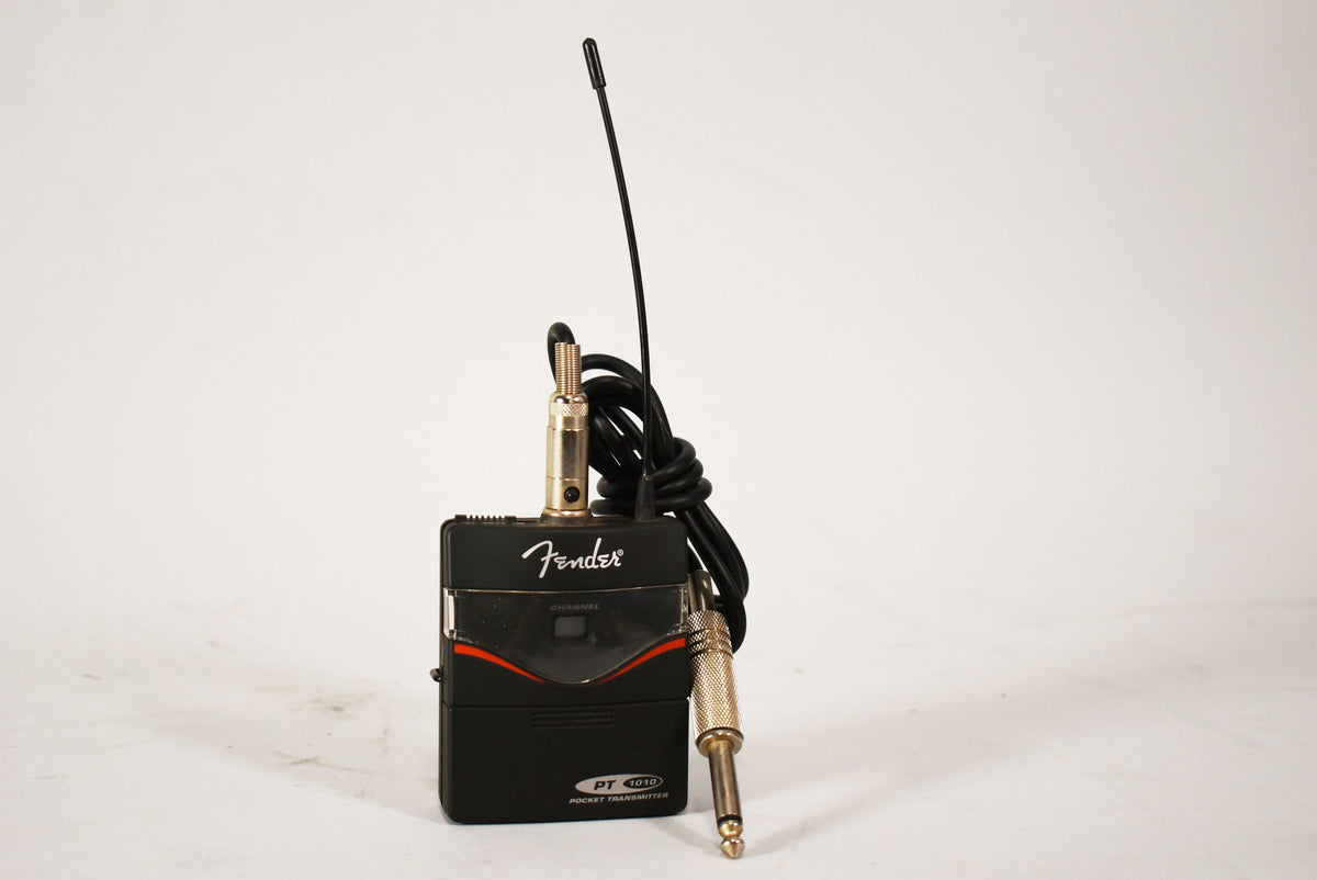 Black wireless transmitter with a flexible antenna, gold-colored input jack, and a red stripe across the front panel, viewed from the front.