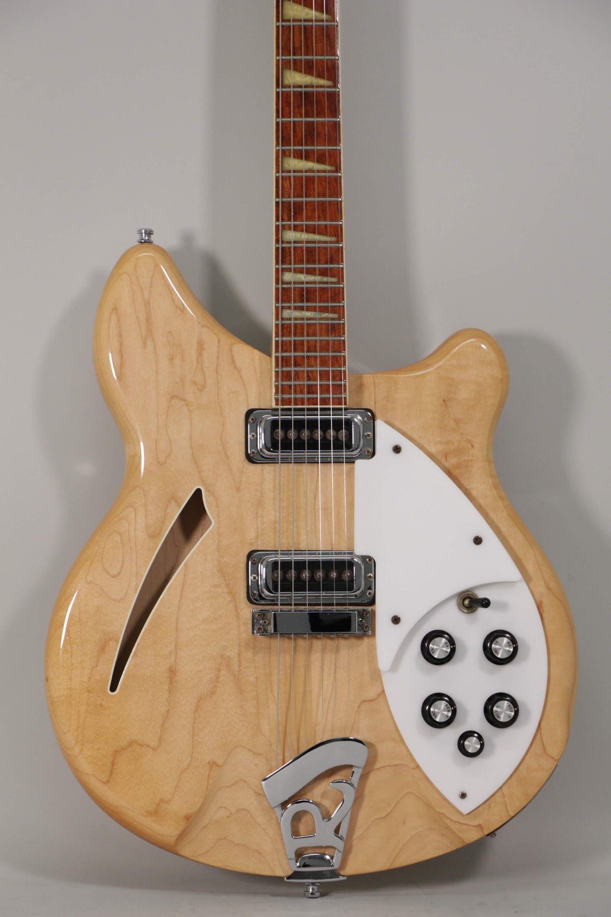 Full-frame view of a glossy blonde hollow-body electric guitar with a white pickguard, chrome hardware, and five black control knobs.