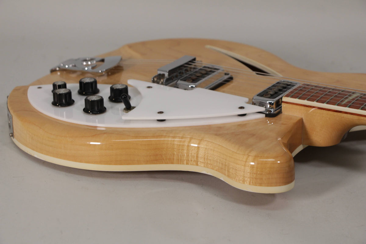 Upper body of a blonde maple guitar with a white pickguard, four black knobs, and a chrome bridge.