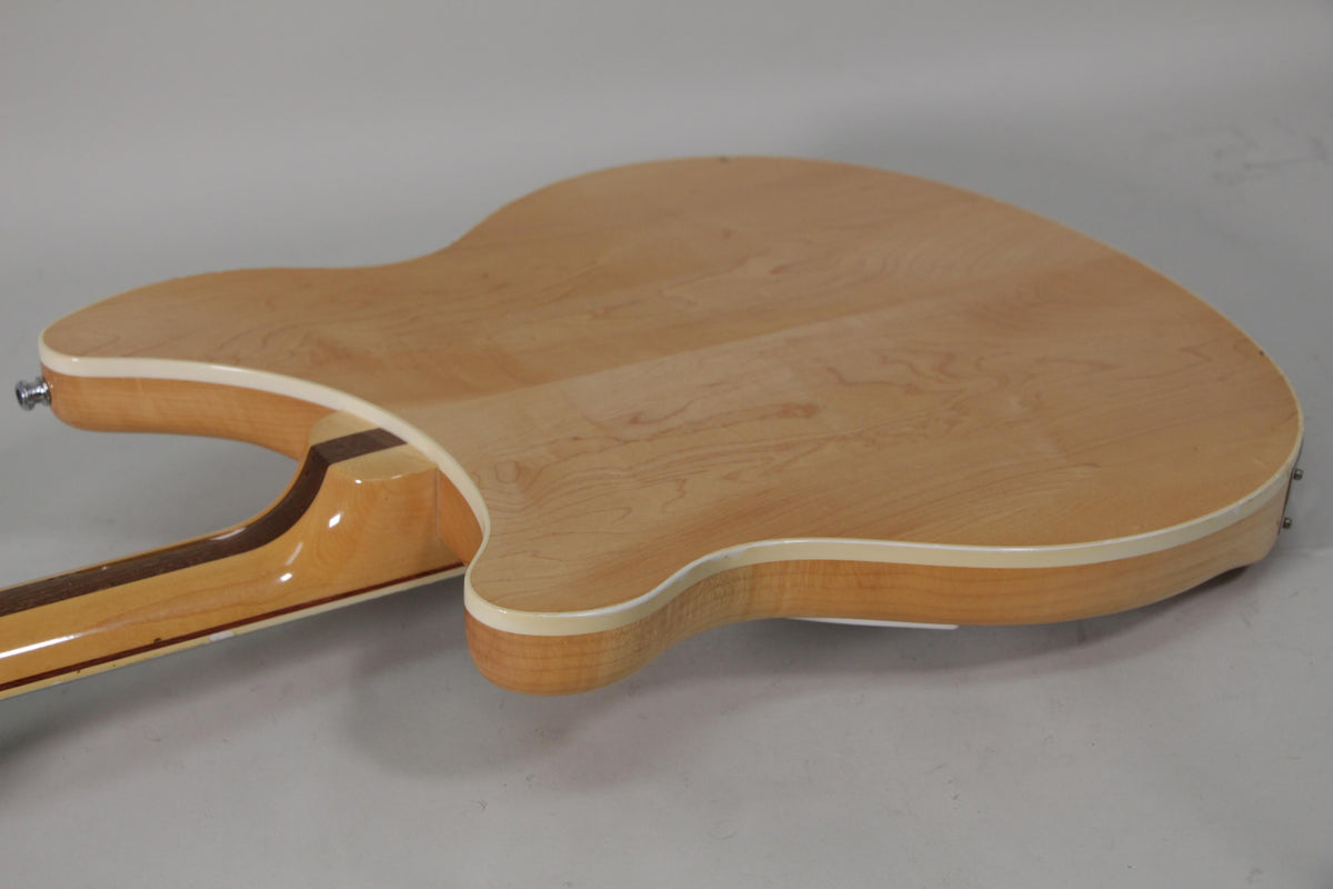 The back of the guitar, in a light maple finish with white binding, shows a slight scuff on the neck heel.