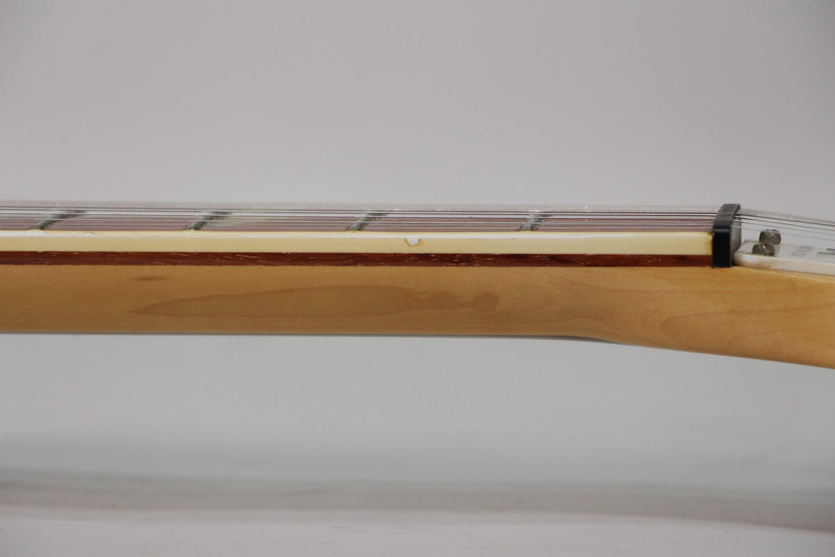 Close-up of the guitar's maple neck and cream binding, showing a small chip in the binding near the third fret.