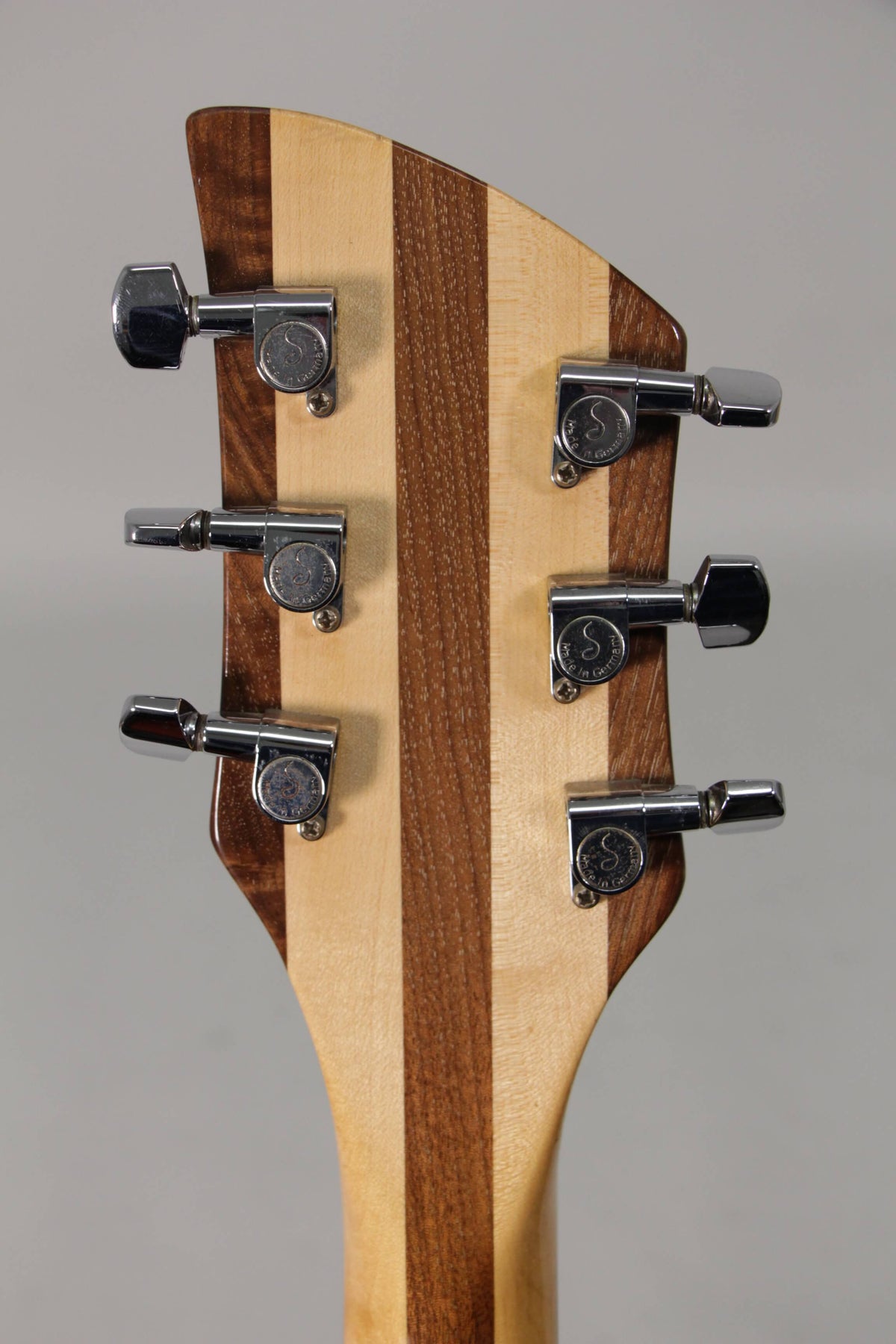 The back of the guitar's headstock shows six chrome tuners on a light and dark striped wood finish, with some light wear on the tuners.