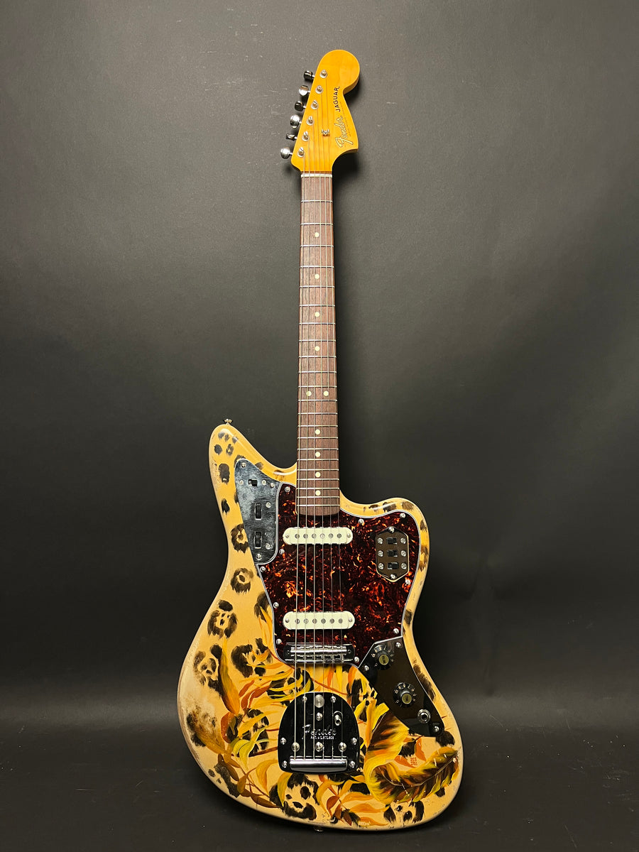 Full-body view of a cream Jaguar guitar with leopard spots and yellow flowers, a tortoiseshell pickguard, and chrome hardware.