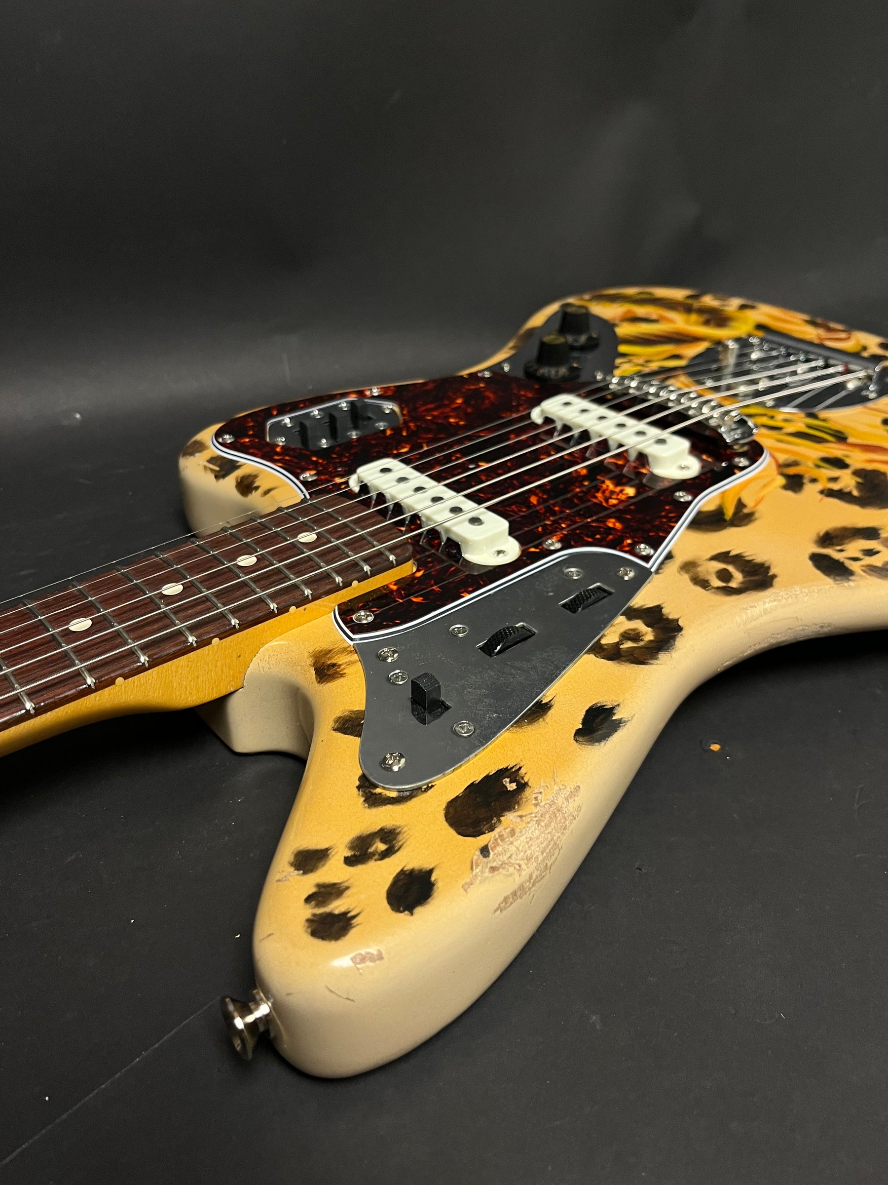 The leopard-print guitar body, with a tortoiseshell pickguard and white pickups, shows visible wear and finish chipping.