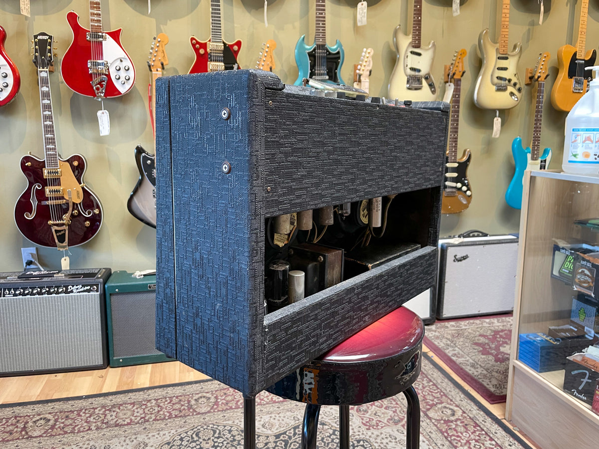The amp is angled to show its dark blue textured side and the open back revealing internal tubes.