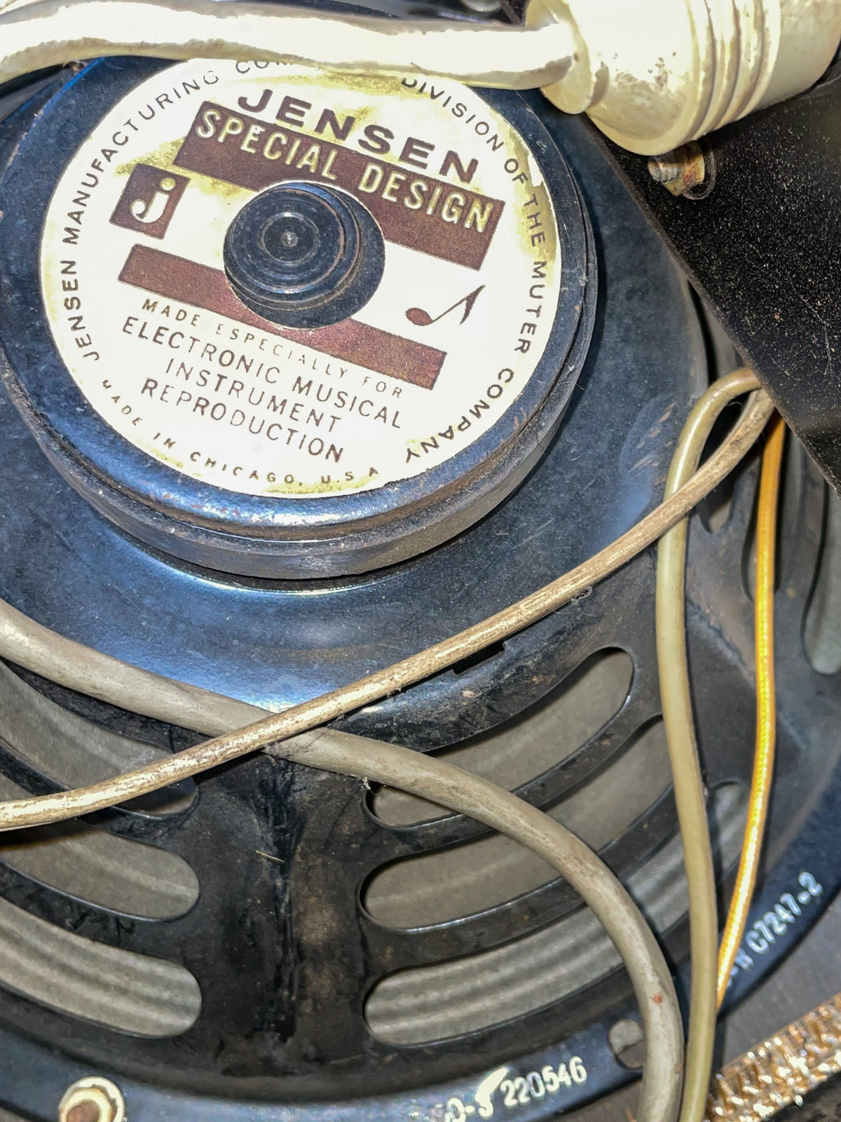 Close-up of a black speaker with a white and brown Jensen Special Design label, showing visible wiring and dust.