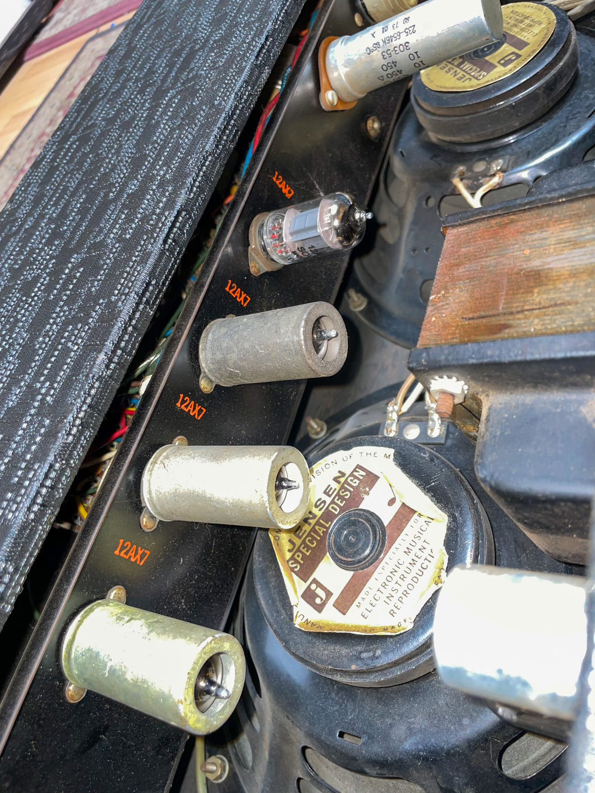 Close-up of the amp's internal components, showing three empty tube sockets, one tube, and a speaker with a worn label.