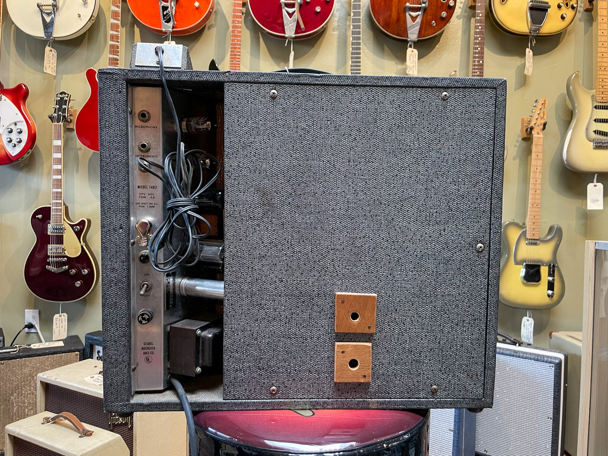 Rear view of the gray tweed amp, showing the exposed silver chassis with inputs, controls, and visible tubes.