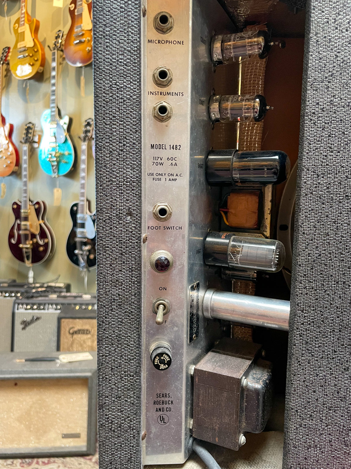Close-up of the amp's silver control panel and exposed tubes, showing input jacks, power switch, and fuse, with some wear.
