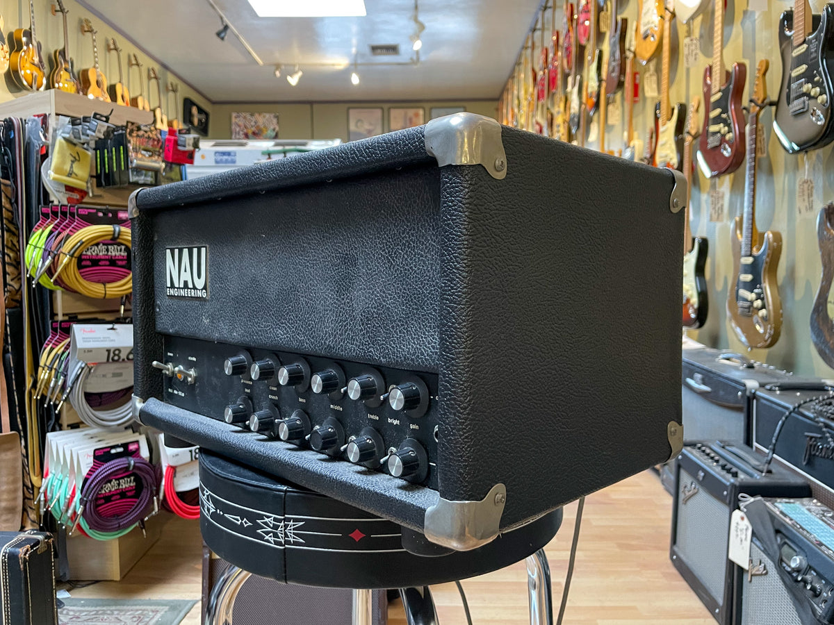 Black textured amp head, angled right, with a silver control panel featuring 12 black knobs and two toggle switches.